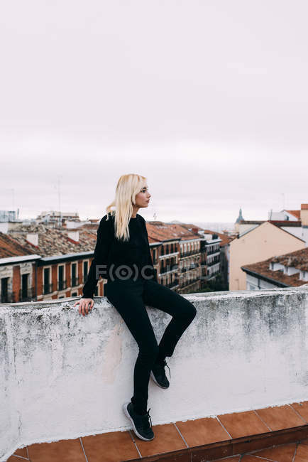 Блондинка сидить на даху — стокове фото