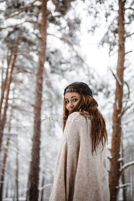 Женщина, оглядывающаяся назад в снежный лес — стоковое фото