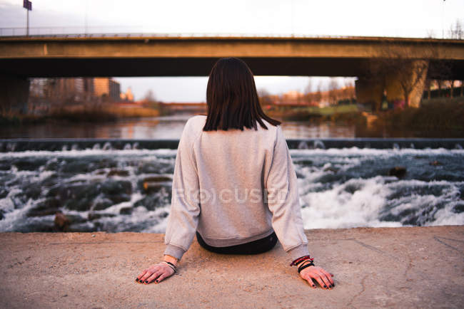 Frau sitzt bei Sonnenuntergang am Wasser — Stockfoto