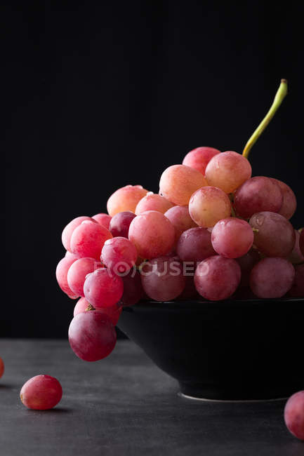Uvas vermelhas em tigela preta — Fotografia de Stock