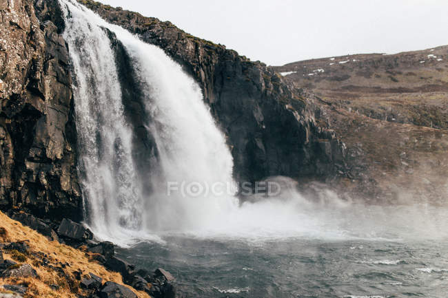 Waterfall rushing down from rocky cliff — Stock Photo