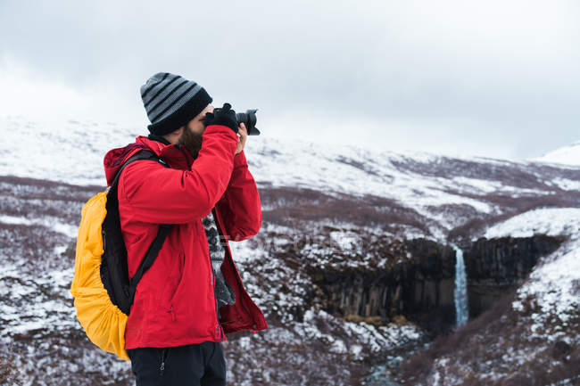 Homme prenant des photos de paysages enneigés — Photo de stock