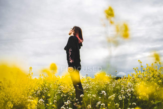 Woman standing on lawn with yellow flowers — Stock Photo