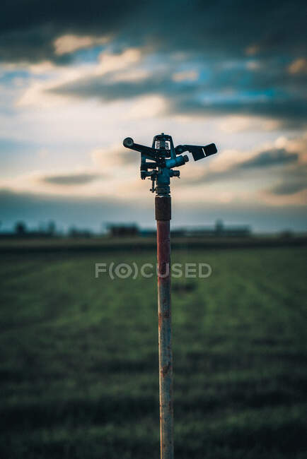 Poste avec équipement d'arrosage placé sur le champ vert sur une ferme. — Photo de stock