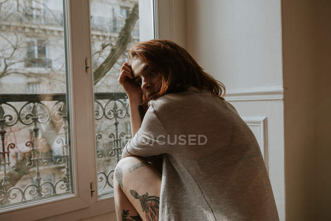 Femme tatouée à la fenêtre — Photo de stock