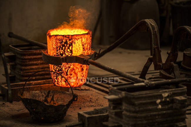 Crop view of male in work clothes standing and preventing coals in oven with burning fire — Stock Photo