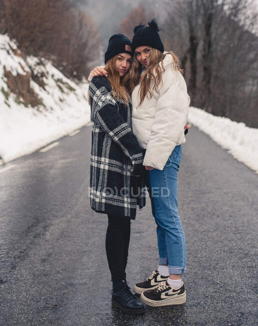 Jovens mulheres bonitas em roupas casuais posando e abraçando no caminho da floresta e olhando para a câmera — Fotografia de Stock