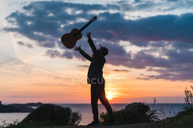 Man having fun with guitar on coast — Stock Photo
