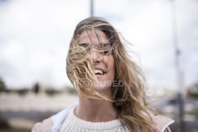 Fröhliche junge Frau schaut weg und setzt draußen Kapuze auf. — Stockfoto