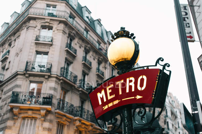 Panneau rouge du métro avec flèche et bâtiment traditionnel, Paris, France — Photo de stock