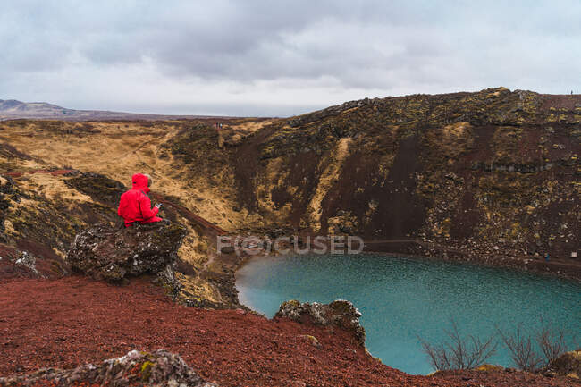 Анонімний чоловік дивиться на маленьке озеро зі смартфоном — стокове фото
