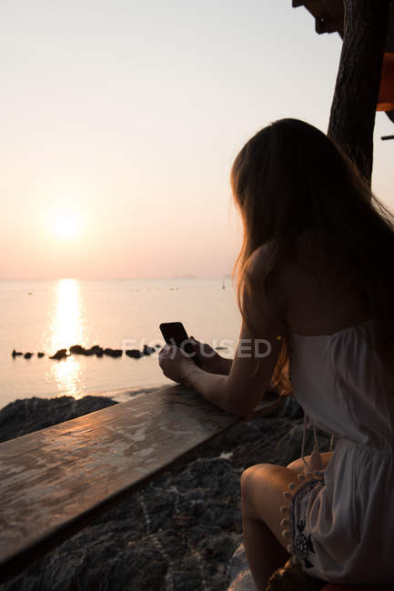 Женщина со смартфоном на берегу моря — стоковое фото