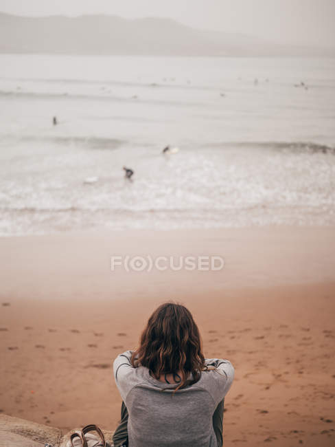 Жінка дивиться на серферів в океані — стокове фото