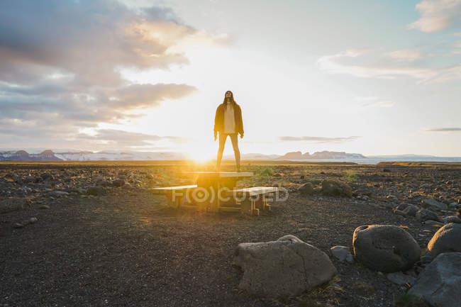 Donna in piedi su un tavolo di legno al tramonto — Foto stock
