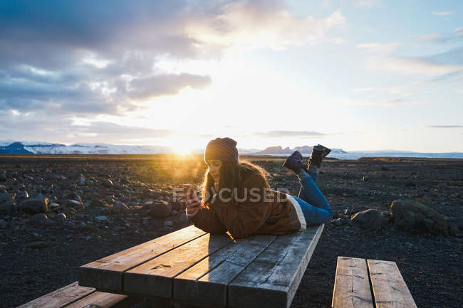 Femme allongée sur une table en bois au coucher du soleil — Photo de stock