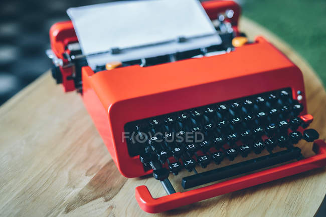 Máquina de escribir roja con hoja de papel insertada - foto de stock