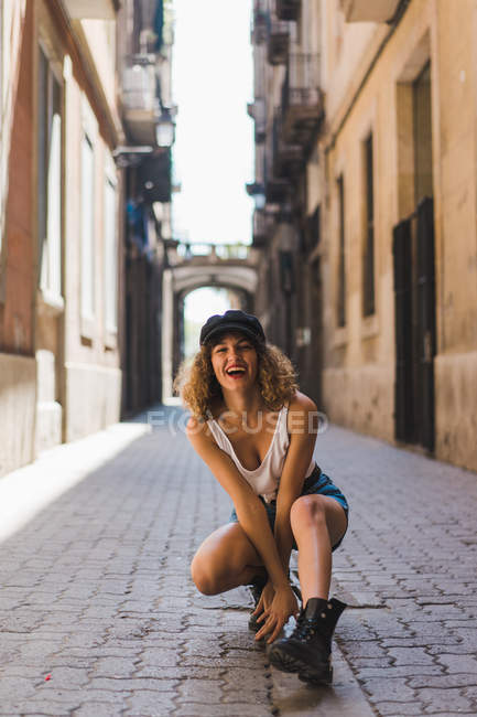 Жінка в чоботях і кепці сидить на вулиці — стокове фото