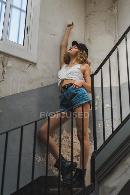 Woman standing in shabby hall on stairs — Stock Photo