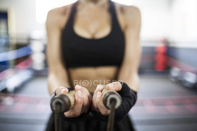 Faceless muscular woman holding wooden jump rope — Stock Photo