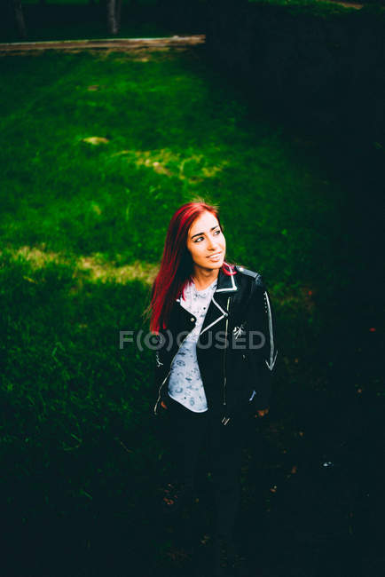 Стильная женщина в куртке, стоящая на траве — стоковое фото