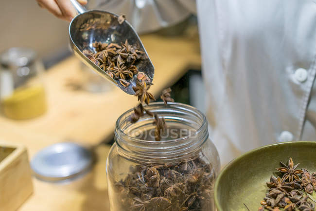 Seller putting anise stars to jar — Stock Photo