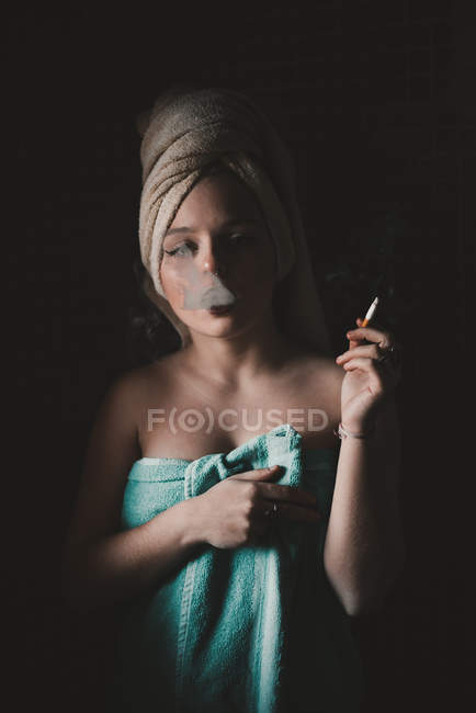 Mujer envuelta en toallas fumando cigarrillo - foto de stock