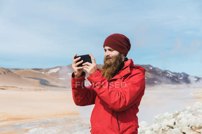 Homem de pé com smartphone no geyser — Fotografia de Stock