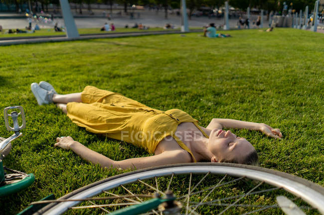 Mulher deitada na grama com bicicleta — Fotografia de Stock