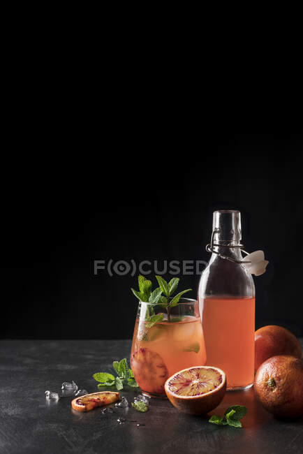 Jug and bottle filled with refreshing lemonade made of red oranges. — Stock Photo