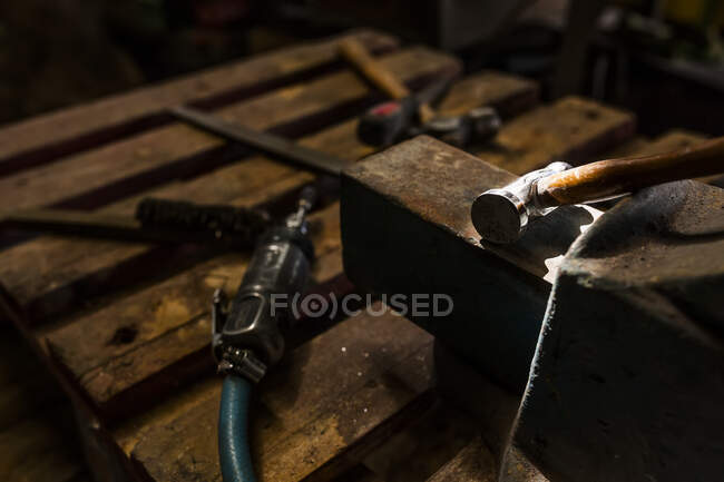 Crop close-up view of hammer lying on metal anvil in casting factory — Stock Photo
