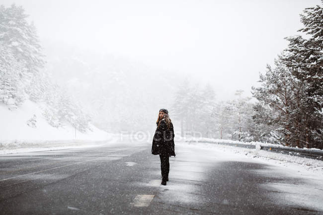 Donna in piedi su strada innevata — Foto stock