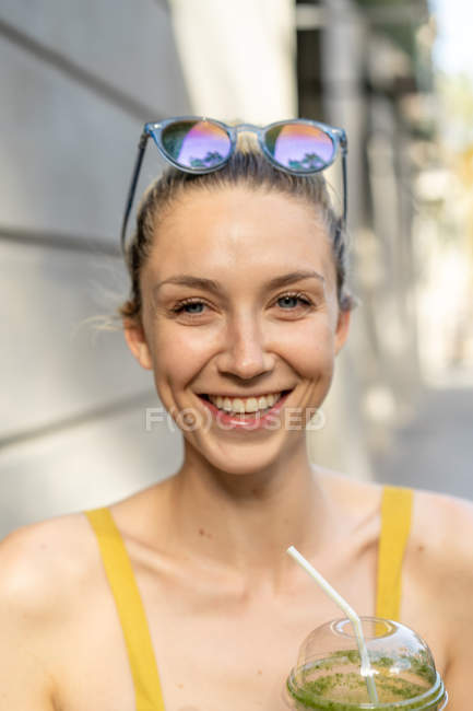 Femme portant des lunettes de soleil debout avec boisson — Photo de stock