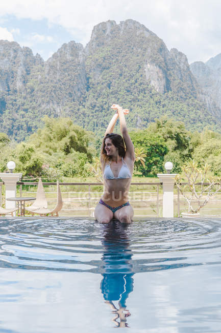 Frau im Bikini sitzt am Pool — Stockfoto