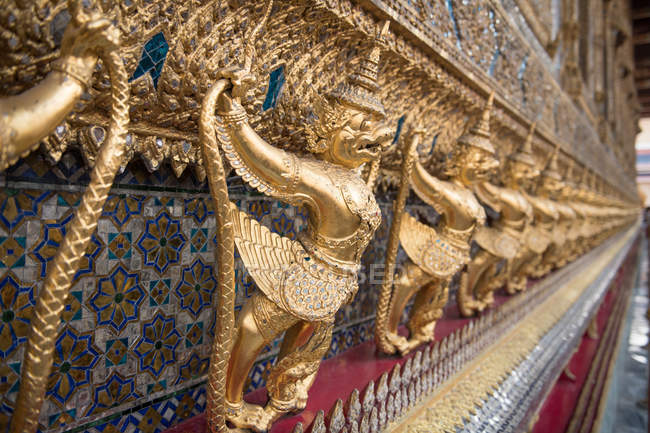 Золотые статуи, удерживающие стену — стоковое фото