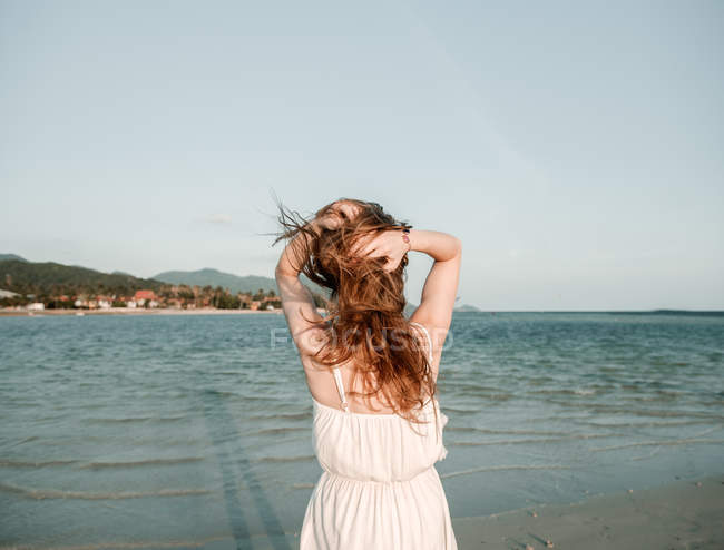 Mulher ajustando o cabelo à beira-mar — Fotografia de Stock