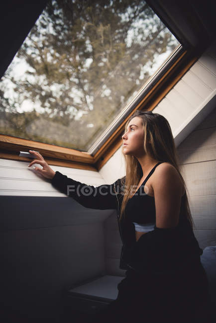Задумчивая женщина смотрит в окно — стоковое фото