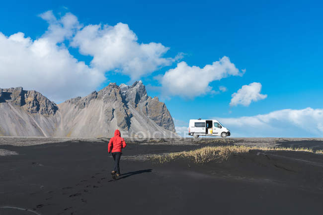 Homem correndo para o carro na praia de areia preta — Fotografia de Stock