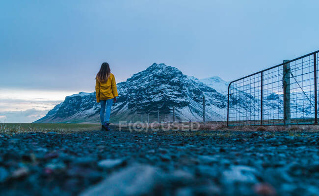 Mulher na estrada para a montanha nevada — Fotografia de Stock