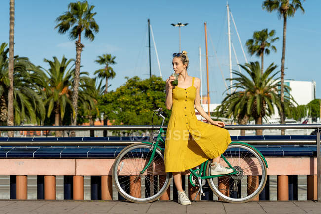 Femme en robe d'été appuyée sur le vélo — Photo de stock