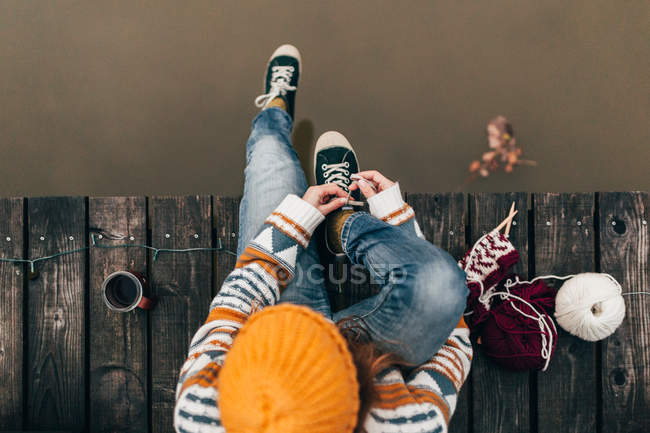 Женщина завязывает шнурки на пирсе у воды — стоковое фото
