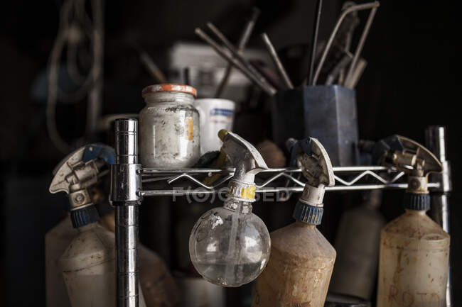 Crop view of stand with sprayer pulverizes glass jars in foundry on black background — Stock Photo
