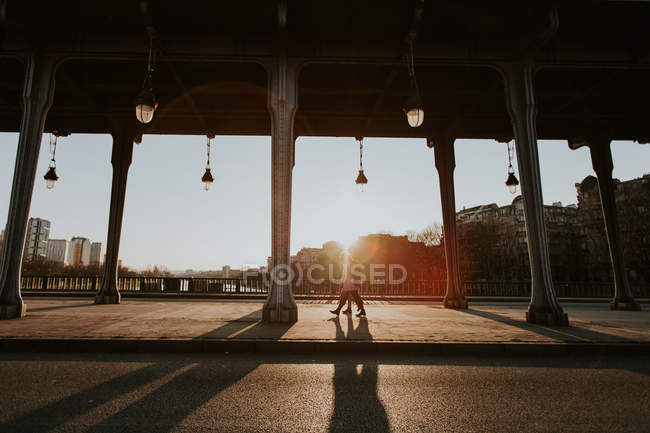 Lanterns and columns on street with people walking on background at sunset — Stock Photo