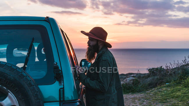 Man standing at car on coast — Stock Photo