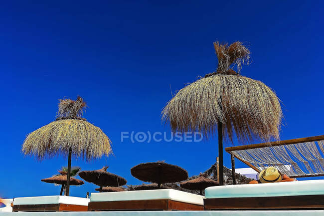 Красивые зонтики стоя на роскошном пляже на фоне ясного голубого неба. — стоковое фото