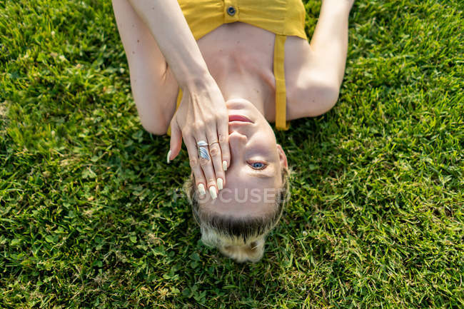 Женщина лежит на траве и покрывает лицо — стоковое фото