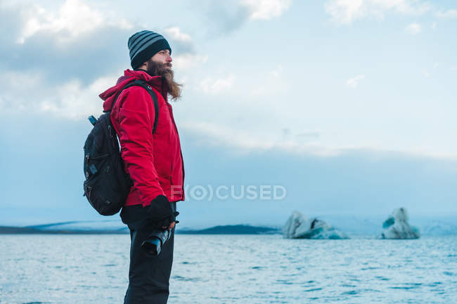 Uomo in abiti caldi in piedi al lago — Foto stock