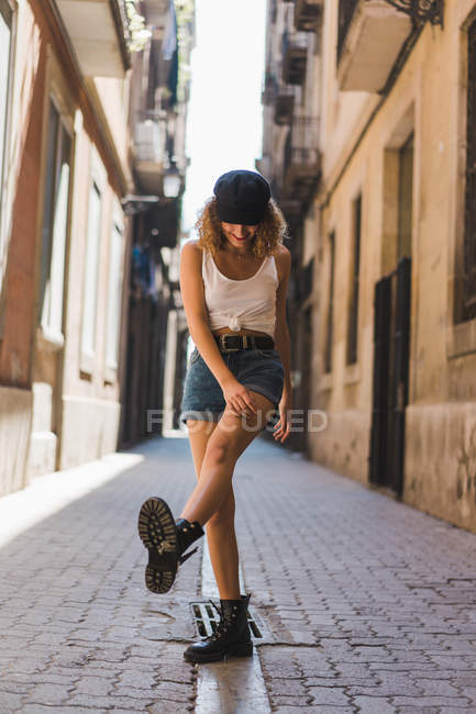 Mulher de pé na rua com perna para cima — Fotografia de Stock