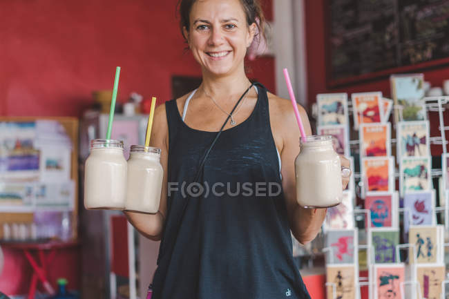 Mulher sorridente segurando frascos de milkshake — Fotografia de Stock