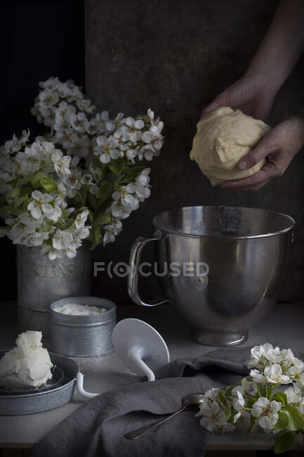 Руки неузнаваемого повара, берущего тесто из миски на кухне. — стоковое фото