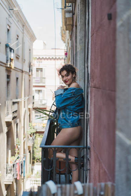 Mujer en chaqueta de mezclilla de pie en el balcón - foto de stock